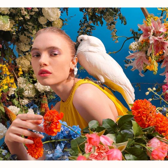 Mujer rodeada de flores y un ave